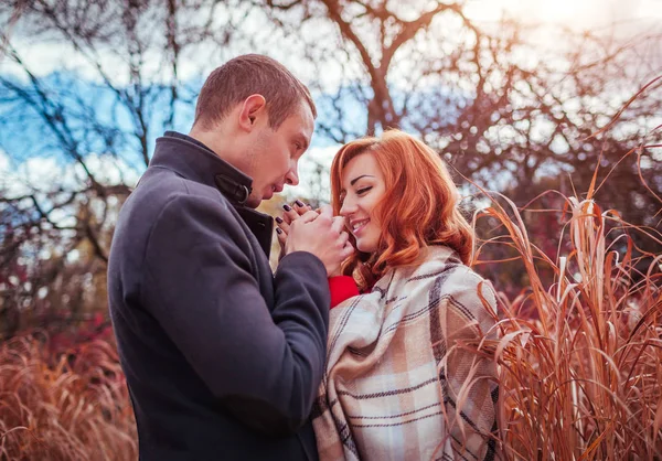 Jongeman verwarmt zijn vriendin handen in herfst bos — Stockfoto