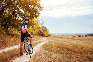 Genç bisikletçi sonbahar alanında sürme