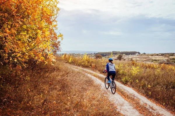 Jovem mulher andando de bicicleta no campo de outono — Fotografia de Stock