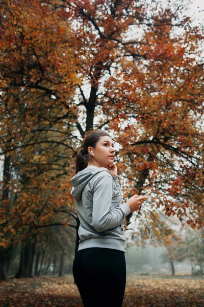 Woman is turning the music on for running in the forest — Stock Photo, Image