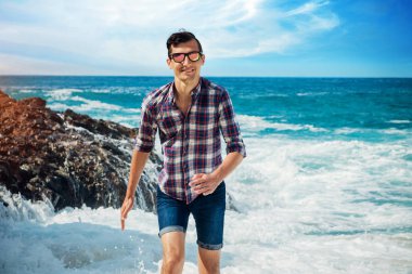 Genç adam uzak dalgalar kumsalda çalışır.