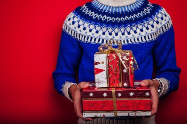 Stüdyo çekim İzlanda kazaklı hediye kutuları yığını tutan genç bir adam. Noel ve yeni yıl kutlama kavramı.