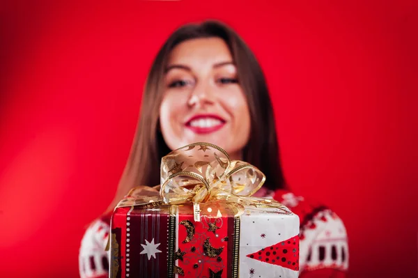 Estúdio de uma jovem em suéter islandês segurando uma caixa de presente. Conceito de celebração de Natal ou Ano Novo . — Fotografia de Stock