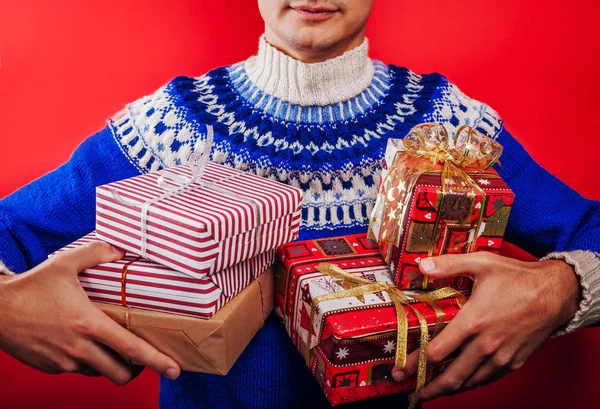 Tournage en studio d'un jeune homme en pull islandais tenant un tas de boîtes-cadeaux. Noel ou Nouvel An concept de célébration . — Photo