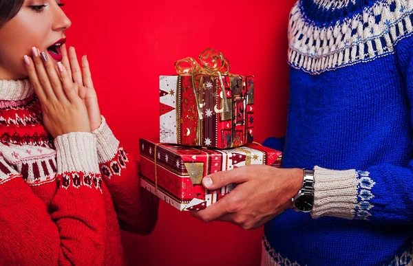 Prise de vue en studio d'un homme en pull islandais donnant des coffrets cadeaux à sa petite amie. Noel ou Nouvel An concept de célébration . — Photo