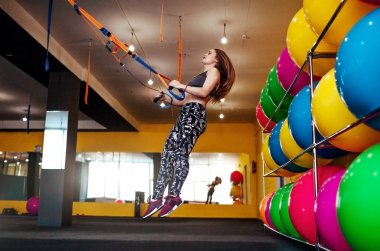 Spor salonunda trx kullanarak egzersizleri yapıyor güzel atletik kadın