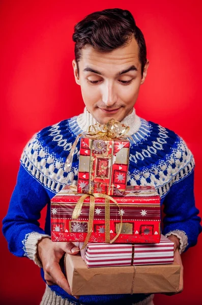 ギフト ボックスのヒープのアイスランド セーターで若い男のスタジオ撮影。クリスマスや新年のお祝いのコンセプト. — ストック写真
