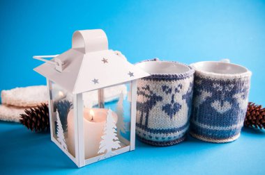 Mavi zemin üzerine örme Noel durumlarda sıcak içecek su bardağı giyinmiş.