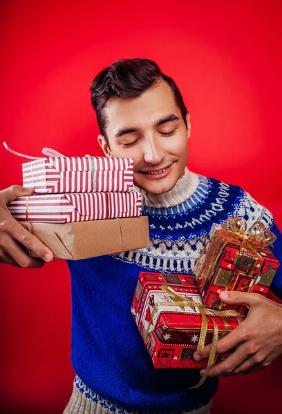 ギフト ボックスのヒープのアイスランド セーターで若い男のスタジオ撮影。クリスマスや新年のお祝いのコンセプト. — ストック写真