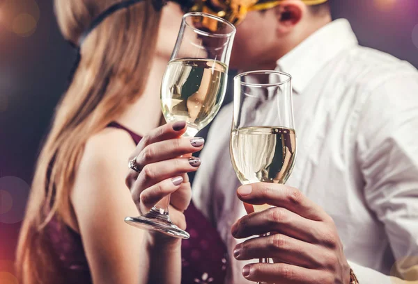 Couple celebrating New Year's eve drinking champagne on masquerade party and kissing