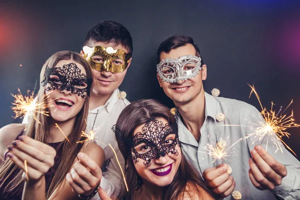 Paar vieren de New Year's eve drinken champagne en verlichting van wonderkaarsen maskerade partij — Stockfoto