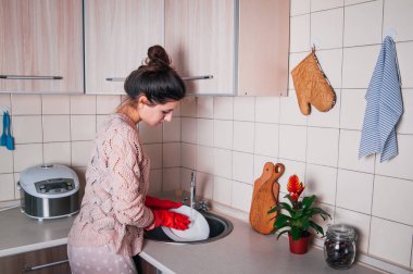 Genç kadın modern mutfakta bulaşık.