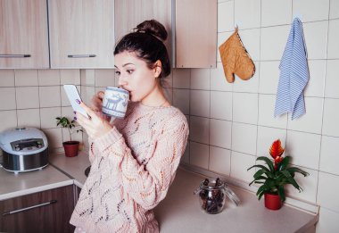 Genç kadın telefonu kullanırken mutfakta Kahvaltı