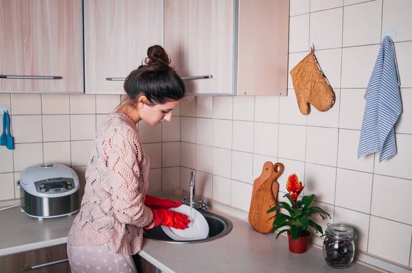 Genç kadın modern mutfakta bulaşık.