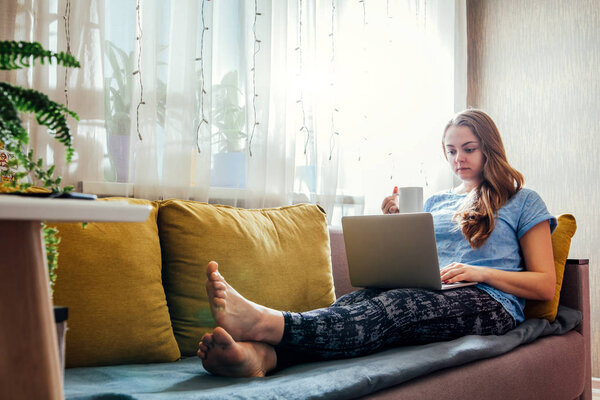 Young woman using her laptop in the livingroom