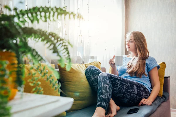 Молодая женщина пьет кофе сидя в гостиной — стоковое фото