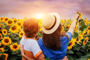 Orta yaşlı anne ve kızı ayçiçeği alanına yürüyor