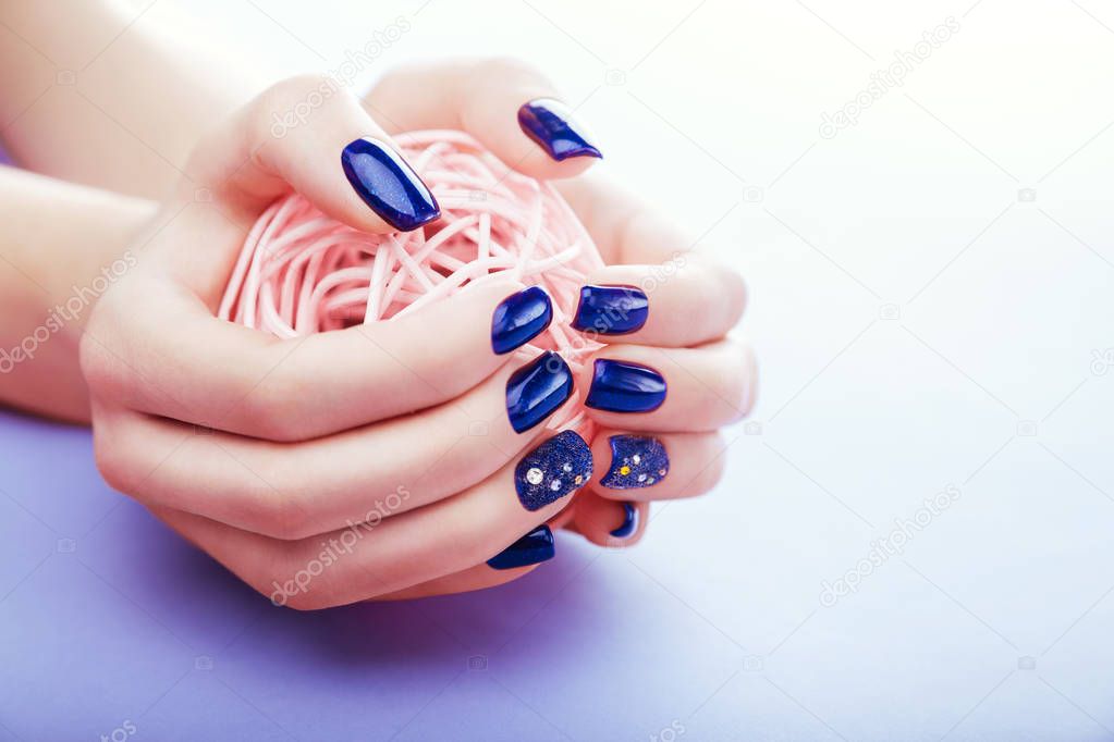 Woman with blue manicure holds a ball