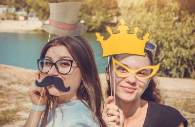 İki genç kadın kullanarak poz fotoğraf booth'den aksesuarlar