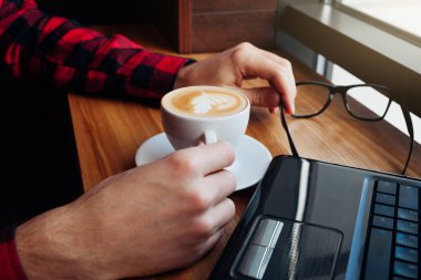 Genç işadamı bir dizüstü bilgisayar kullanarak kafede kahve sahiptir