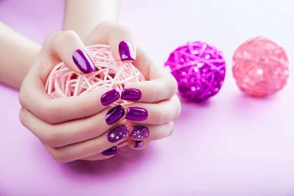 Donna con manicure viola tiene una palla — Foto Stock