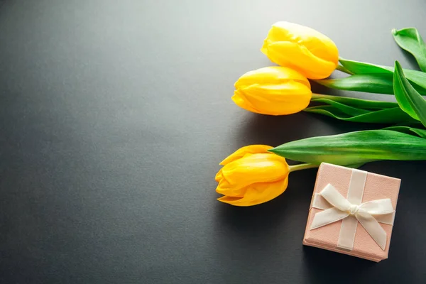 Een geschenkdoos met tulpen op grijze achtergrond — Stockfoto