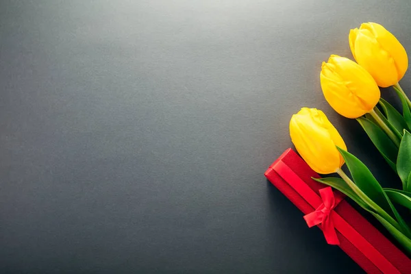 Een geschenkdoos met tulpen op grijze achtergrond — Stockfoto