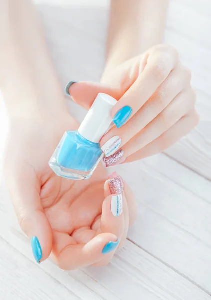 Femme avec manucure pastel tenant vernis à ongles bleu. Traitement de la peau et concept de soins du corps . — Photo