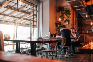 Loft kafede asılı mutlu Arapça genç adamlar. Grup lounge barda konuşurken karışık ırk insan