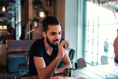 Loft kafede asılı mutlu Arap genç adamlar. Çay içme cam kenarında lounge barda konuşan arkadaşlar