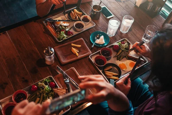 Молодий чоловік фотографує свою їжу для соціальної мережі під час сніданку в кафе. Концепція інтернет-залежності . — стокове фото
