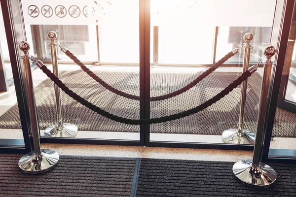 Баррикада металлической стойки с бархатной веревкой перед стеклянными дверями. Закрытый вход в торговый центр — стоковое фото