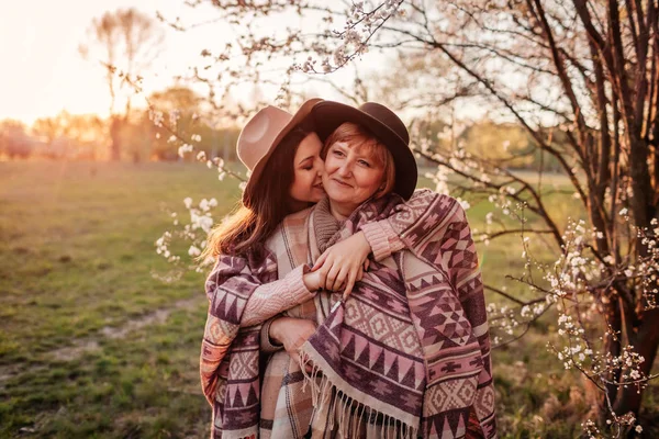 Madre de mediana edad y su hija adulta abrazándose en el floreciente jardín. Concepto del día de la madre. Valores familiares —  Fotos de Stock