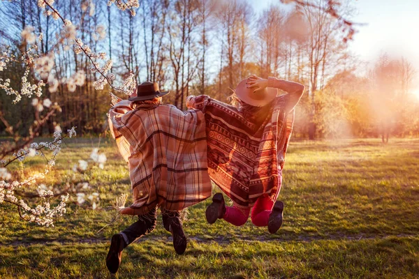 Mère d'âge moyen et sa fille adulte sautant dans le jardin fleuri. Concept de fête des mères. Les femmes s'amusent — Photo