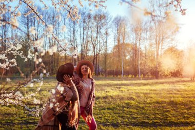 Orta yaşlı anne ve yetişkin kızı çiçek açan bahçede yürüyüş. Anneler günü kavramı. Aile değerleri