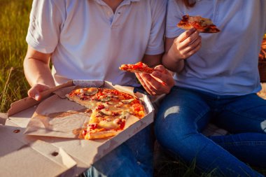 Genç bir çift dışında pizza yemek. Kadın ve adam günbatımında piknik. Fast food kavramı. Yakın çekim