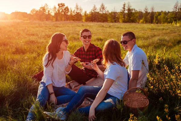 Amigos saliendo y comiendo pizza afuera. Mujeres y hombres de picnic al atardecer. Chicos divirtiéndose . —  Fotos de Stock