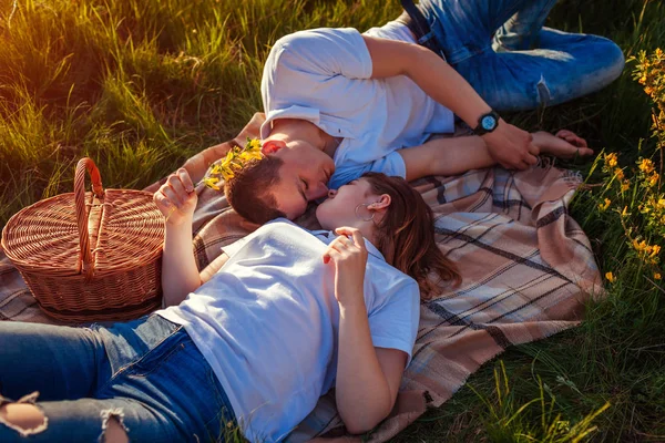 年轻夫妇野餐后放松。女人和男人躺在草地上, 在日落说话。家伙冷了出来 — 图库照片