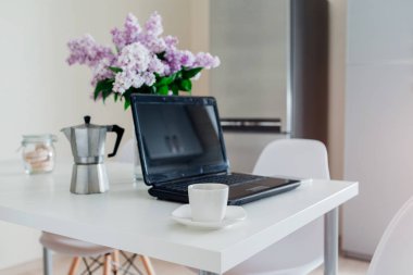 Laptop modern mutfakta kahve yaparken kullanıyor. Kahvaltı bir freelancer