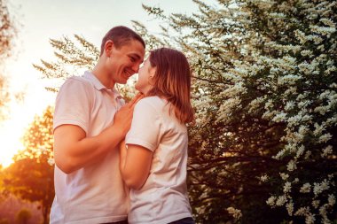 Mutlu çift günbatımında bahar çiçek açan Park'ta yürüyordunuz. Genç adam ve kadın elele