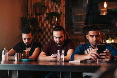 Sosyal medya bağımlılık kavramı. Onların telefon lounge barda bakarak karışık yarış arkadaşlar. Arkadaşlar arasında yalnızlık. Arap çocuklar smarphones kullanarak