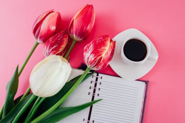 Bir fincan kahve esspresso ve pembe bir arka plan üzerinde taze Lale ile defter. Yazma planı süre Kahvaltı