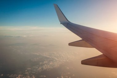 Deniz ve uçak kanadıyla çevrili bulutların ve adaların uçak penceresi manzarası. Seyahat kavramı