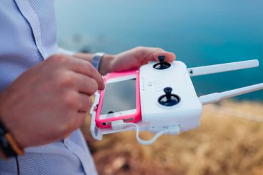 Uzaktan kumanda. Helikopter kontrolörüyle akıllı telefon kullanan bir adam. Hava video çekimi