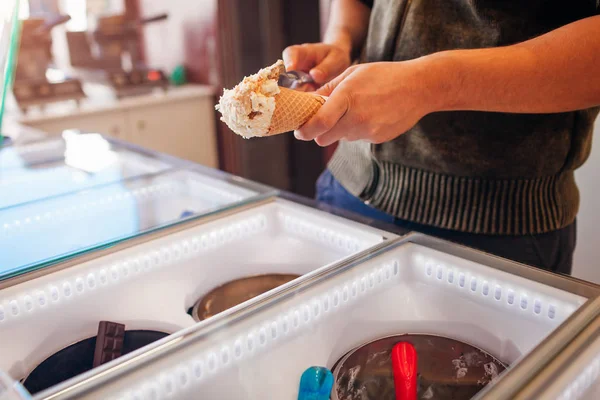 Verkäufer füllen Waffelkegel mit Eis. Vanillearoma mit Kekskrümeln — Stockfoto