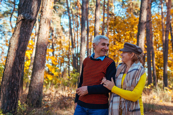 Осенняя прогулка. Старшая пара, гуляющая в осеннем парке. Счастливые мужчина и женщина говорят и расслабляются на открытом воздухе
