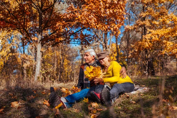 Diversão da época de outono. Casal sénior a abraçar-se sentado no parque. Homem e mulher relaxando ao ar livre — Fotografia de Stock