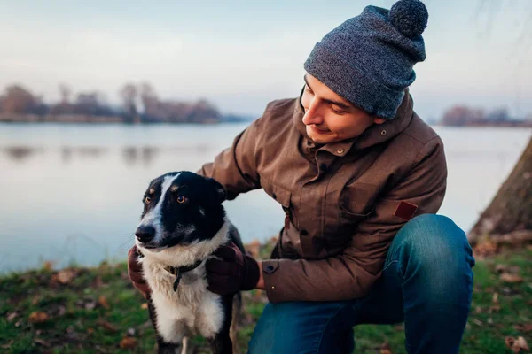 Uomo che gioca con il cane nel parco autunnale in riva al lago. Felice animale domestico divertirsi all'aperto — Foto Stock