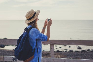 Yunanistan 'ın Santorini adasındaki Akrotiri' de Vlychada plajında yürüyen bir kadın gezgin. Deniz fotoğrafı çeken bir turist