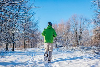 Koşan sporcu kış ormanlarında koşuyor. Karlı havada dışarıda antrenman. Aktif ve sağlıklı bir yaşam tarzı. Spor.
